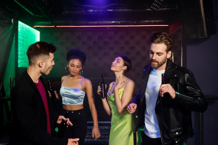 Szerokie, panoramiczne ujęcie naszej głównej sali gier w Club Hall Society, zrobione z perspektywy wejścia podczas trwającej, weekendowej imprezy. Setki kolorowych żarówek i neonów odbijają się w kieliszkach gości, tworząc niezwykle ciepłą, magiczną aurę sprzyjającą doskonałej zabawie. Każdy stolik jest całkowicie zapełniony przez entuzjastycznych graczy w różnym wieku, co dowodzi ogromnej popularności naszego lokalnego klubu w Polsce. To miejsce dosłownie tętni życiem, radosnymi rozmowami i wielkimi emocjami towarzyszącymi każdemu kolejnemu losowaniu.